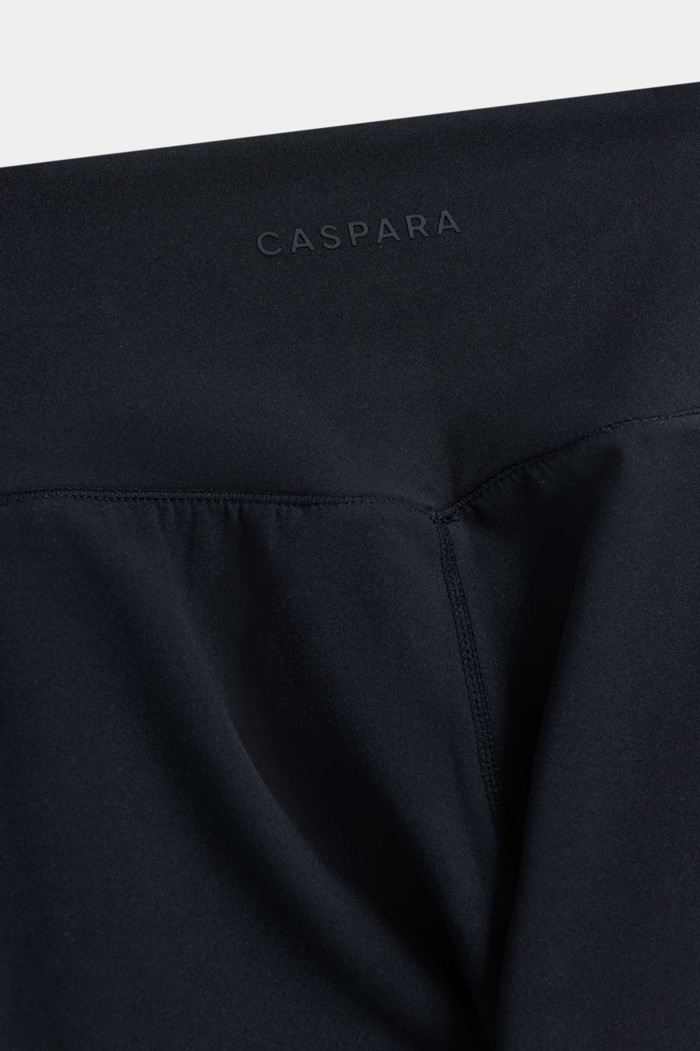 Close-up of the back waistband and logo detail on black CASPARA Cloudform leggings.